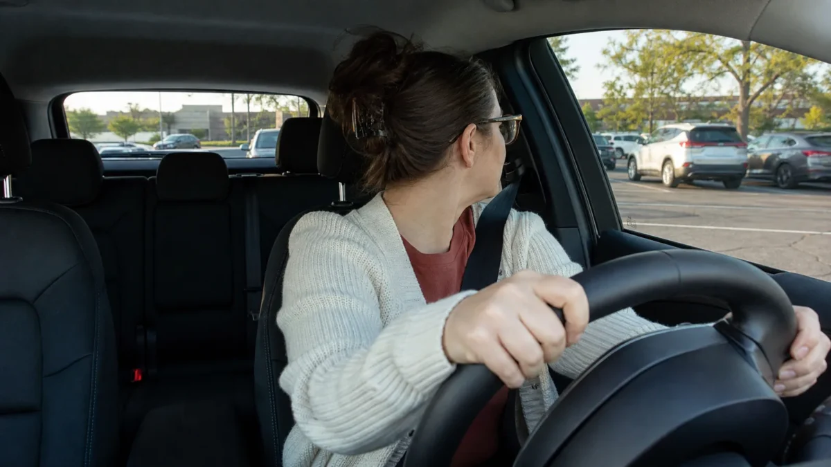 A driver looking back over their right shoulder through the rear window while reversing a car out of a parking space in Ontario.